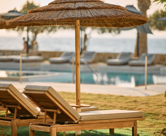 Paralos Kosta Alimia two sunbeds with umbrella and the pool blurred in the background