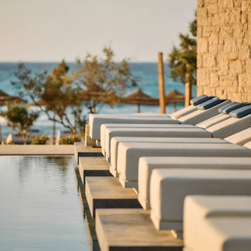 Paralos Kosta Alimia photo of white sunbeds with blue headrests and the sea in the background