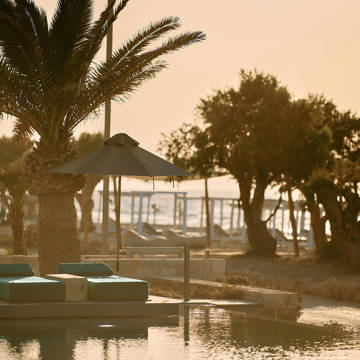 Paralos Kosta Alimia pool's green sunbeds and the beach in the background