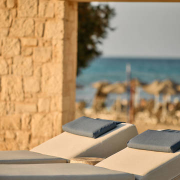 Paralos Kosta Alimia photo focused on two white sunbeds with blue headrests