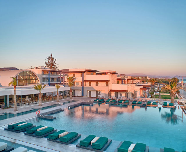 Paralos Kosta Alimia big pool with green sunbeds and a hotel building in the background